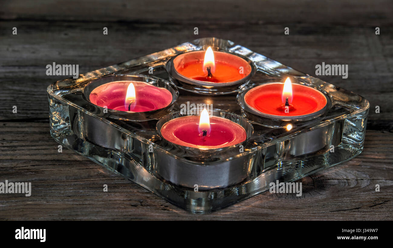 Four lighted candles in a holder Stock Photo