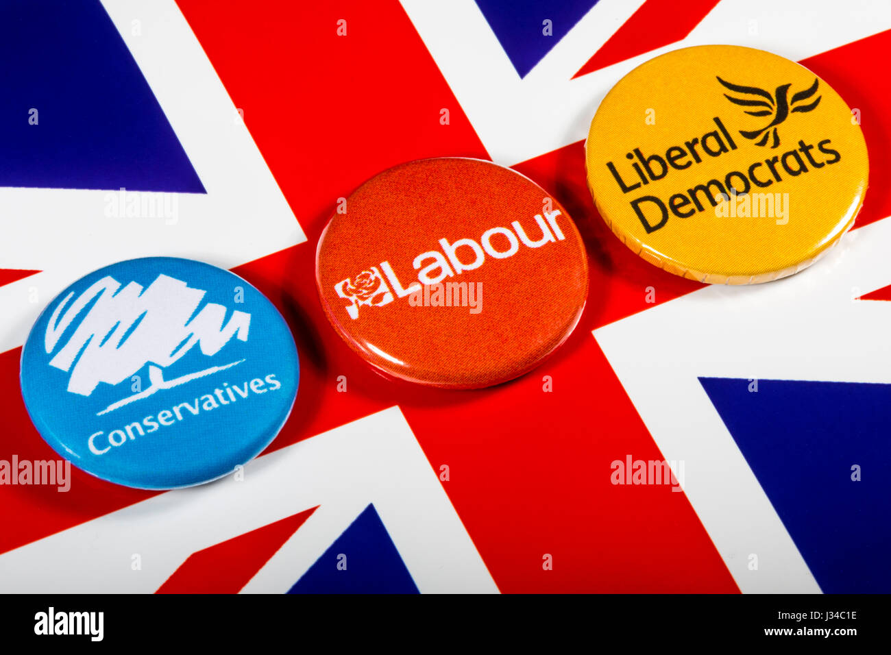 LONDON, UK - MAY 2ND 2017: Conservatives, Labour and Liberal Democrat pin badges over the UK flag, symbolizing the political battle for the General El Stock Photo