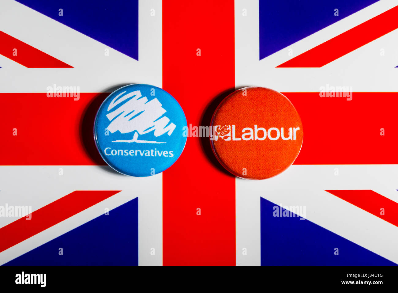 LONDON, UK - MAY 2ND 2017: Conservative and Labour Party pin badges over the UK flag, symbolizing the political battle for the General Election, on 2n Stock Photo