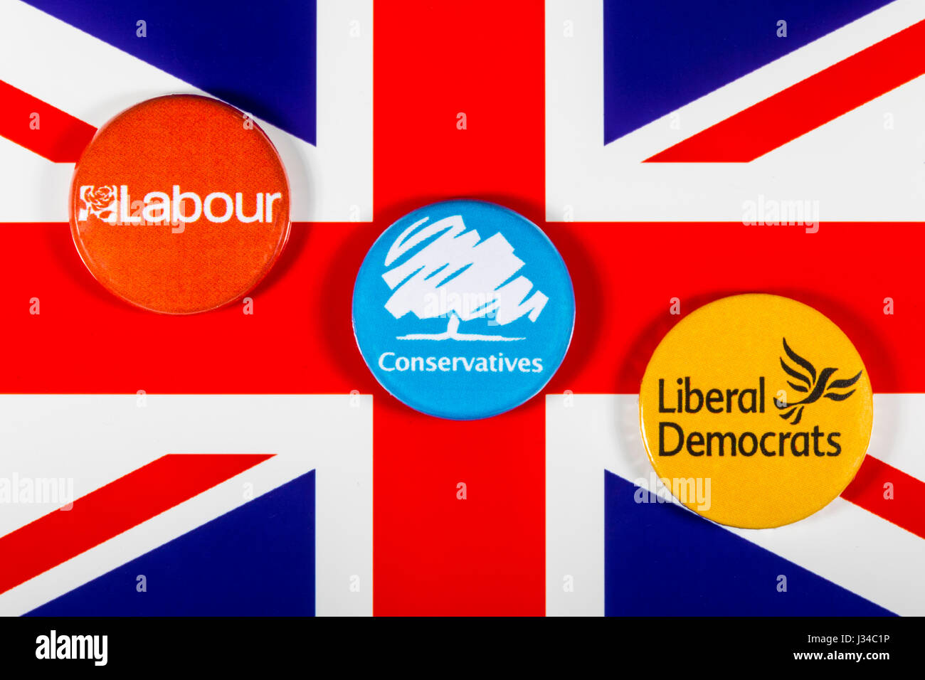 LONDON, UK - MAY 2ND 2017: Labour, Conservatives and Liberal Democrat pin badges over the UK flag, symbolizing the political battle for the General El Stock Photo