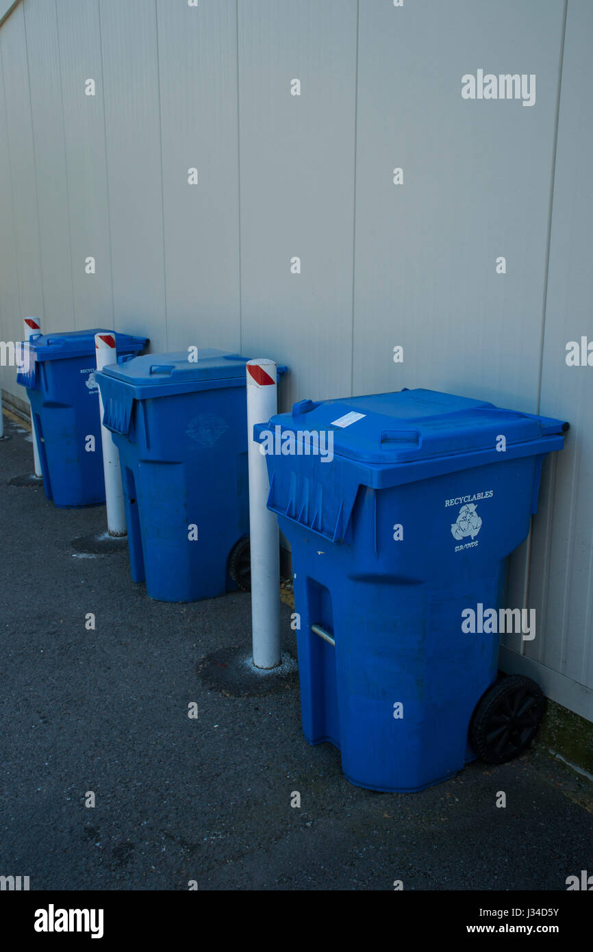 Blue, wheeled, recycling bins against a wall Stock Photo Alamy