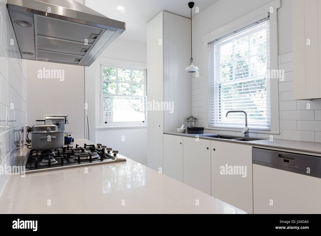 New renovated crisp white galley style kitchen in Australian apartment Stock Photo