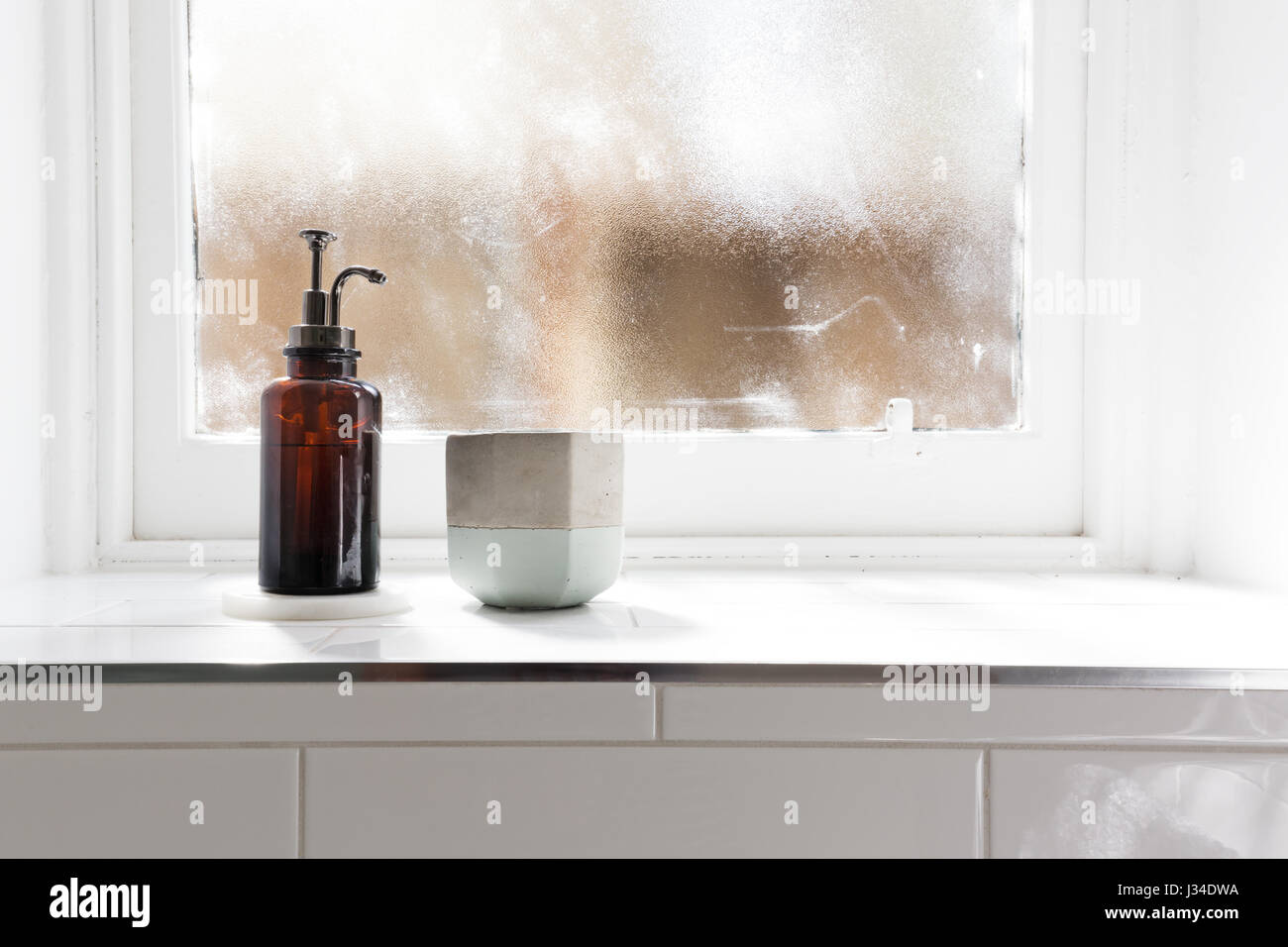 Bathroom soap dispenser and pot on window ledge with background of