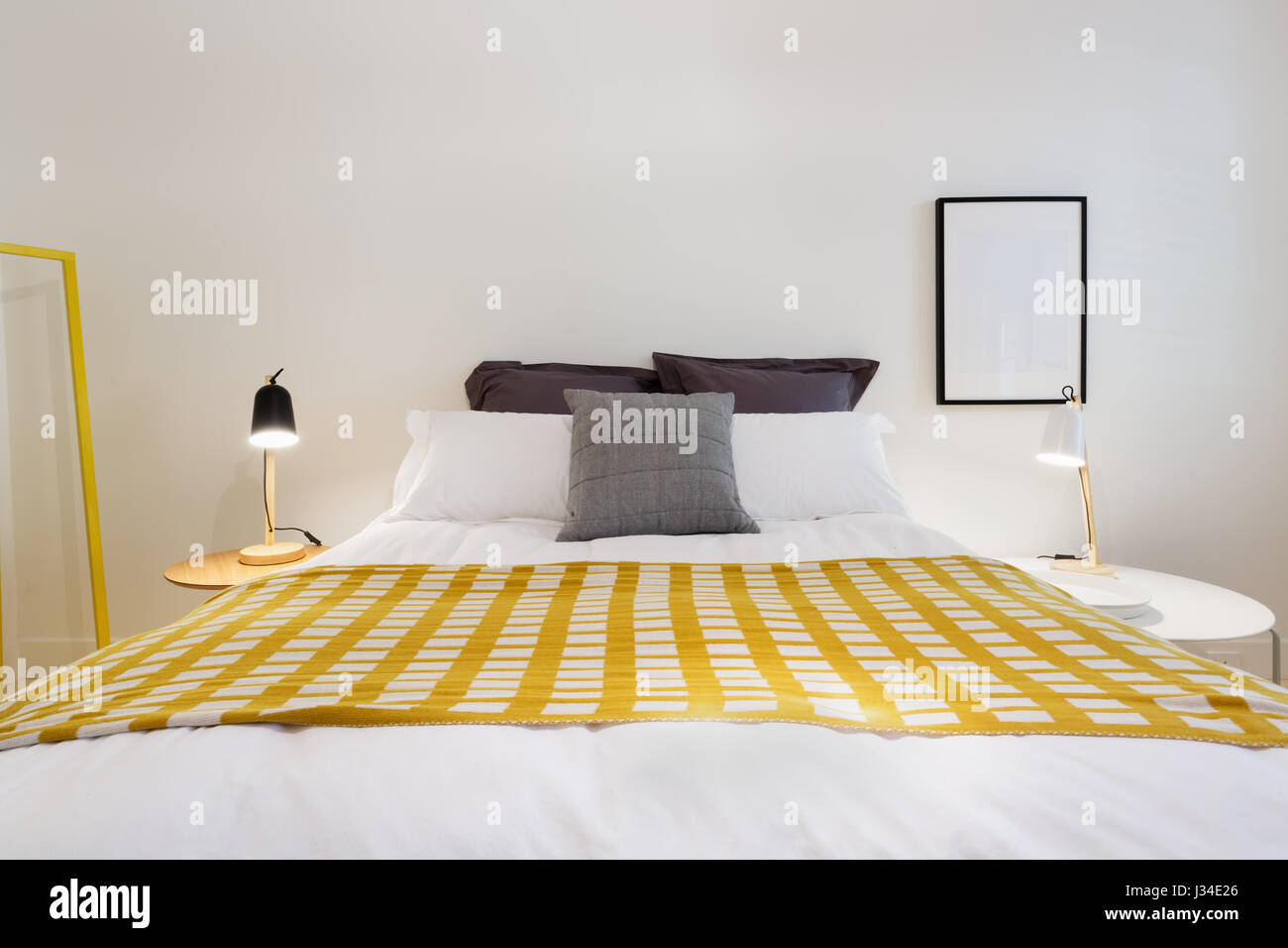 Yellow accent decor throw rug in contemporary styled white bedroom Stock Photo