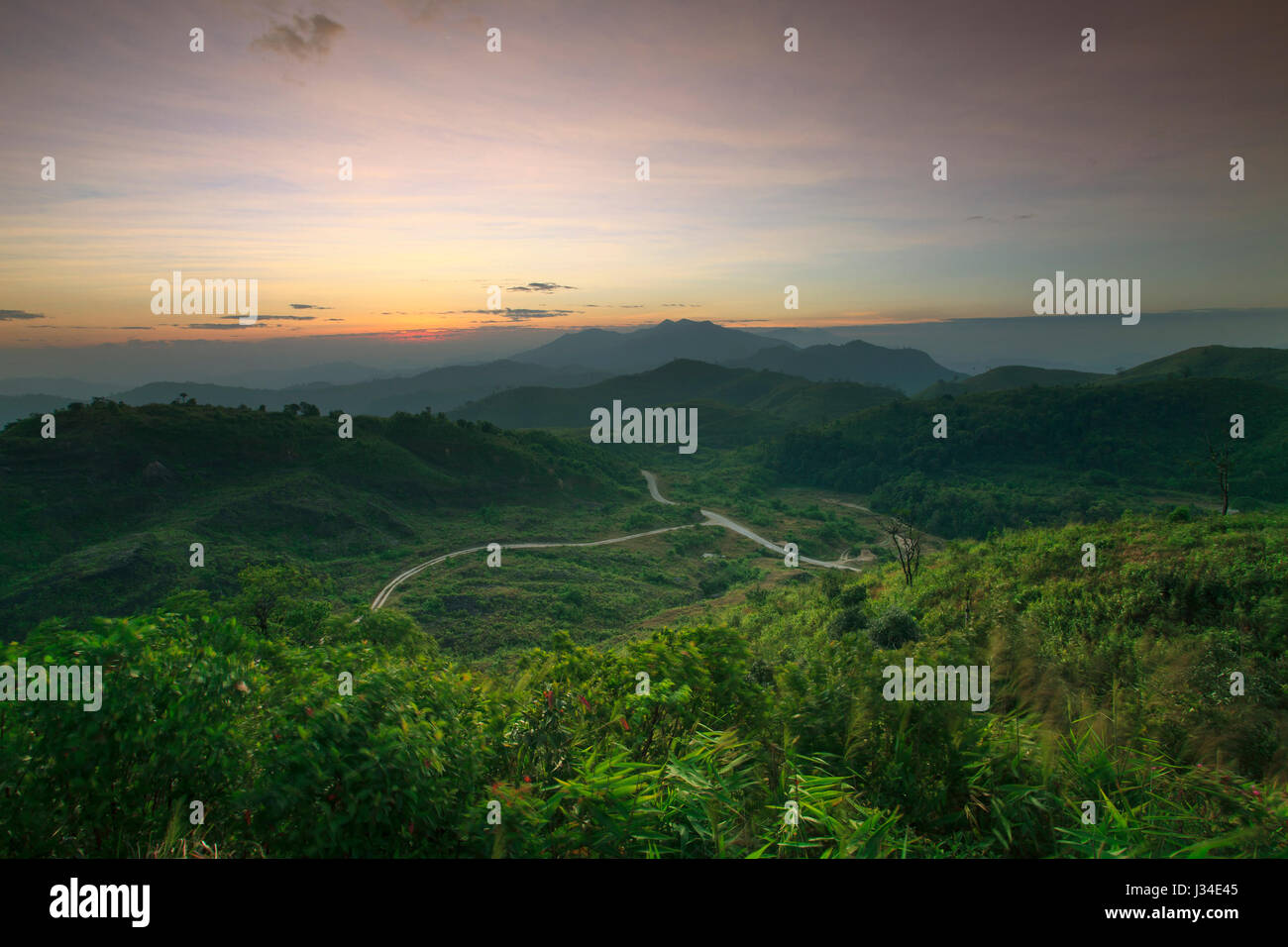 landscape scene of natural mountain and rural roads through the forest with sun rising in morning sky use as nature background,backdrop Stock Photo