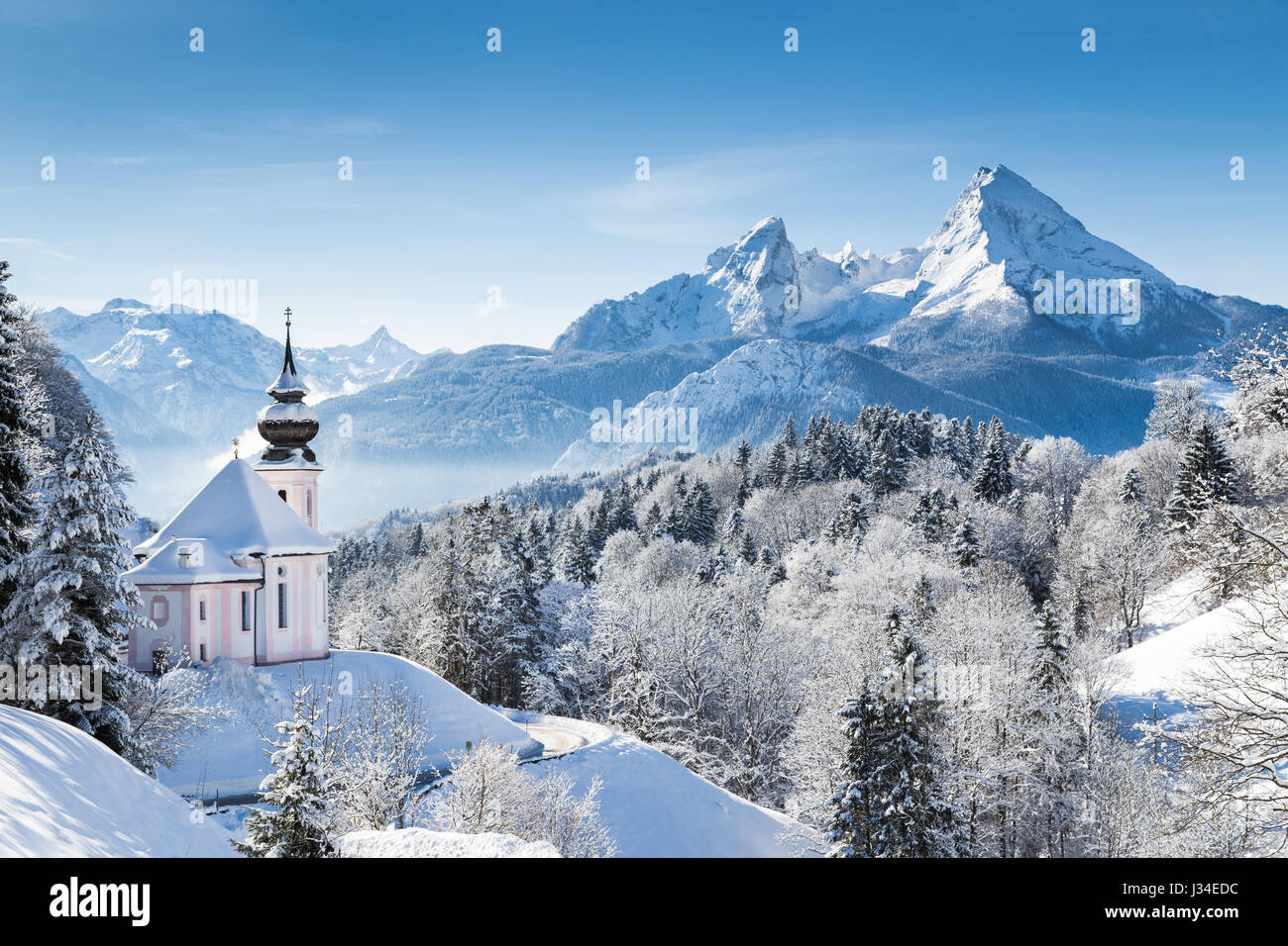 Panoramic view of beautiful winter wonderland mountain scenery in the Alps with pilgrimage church of Maria Gern and famous Katzmann summit, Bavaria Stock Photo