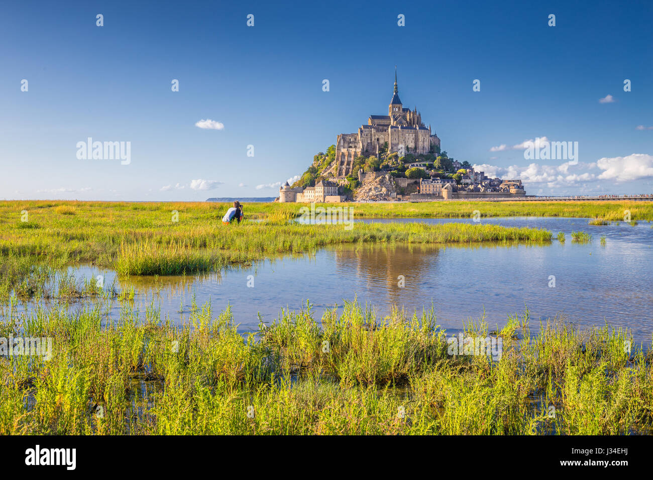 Classic view of famous historic Le Mont Saint-Michel tidal island on a sunny day with blue sky and clouds in summer, Normandy, northern France Stock Photo