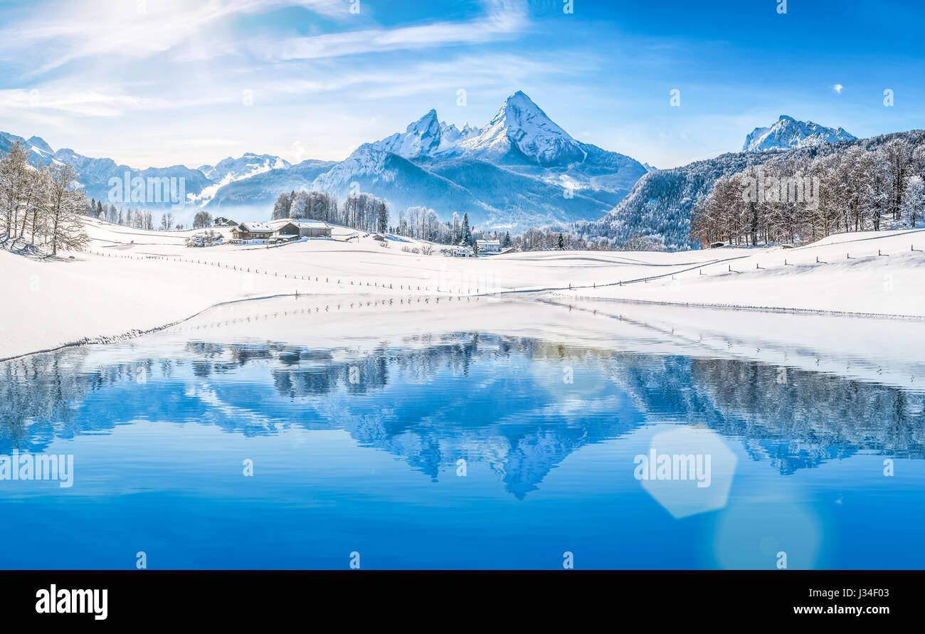 Panoramic view of beautiful white winter wonderland scenery in the Alps with snowy mountain summits reflecting in crystal clear mountain lake Stock Photo