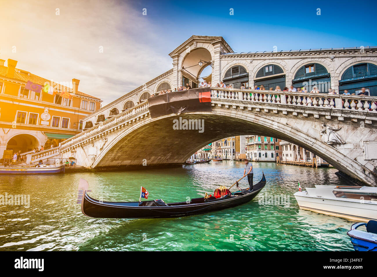 Beautiful view of traditional Gondola on famous Canal Grande with Rialto Bridge at sunset in Venice, Italy Stock Photo