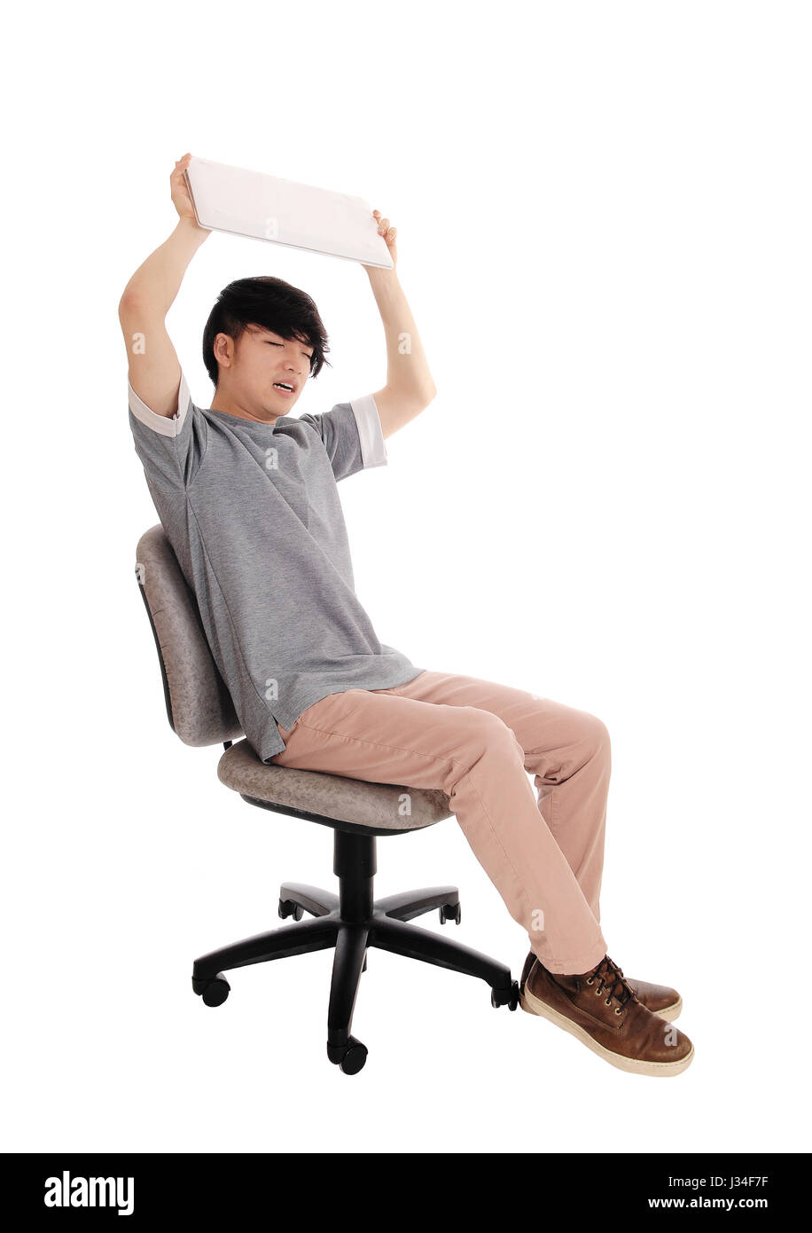 A young Asian teenager sitting on a office chair with his laptop in his