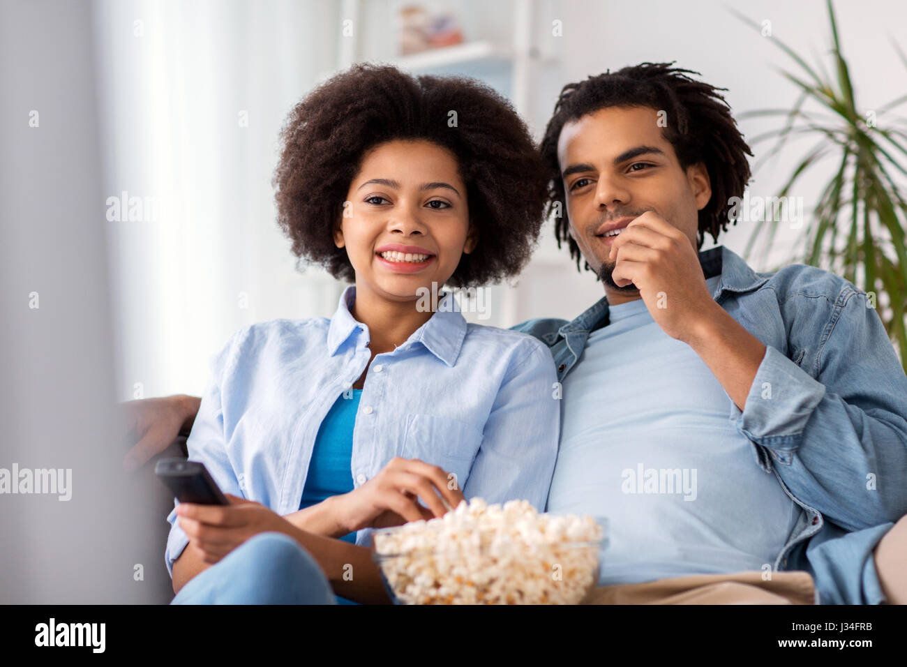 smiling couple with popcorn watching tv at home Stock Photo - Alamy