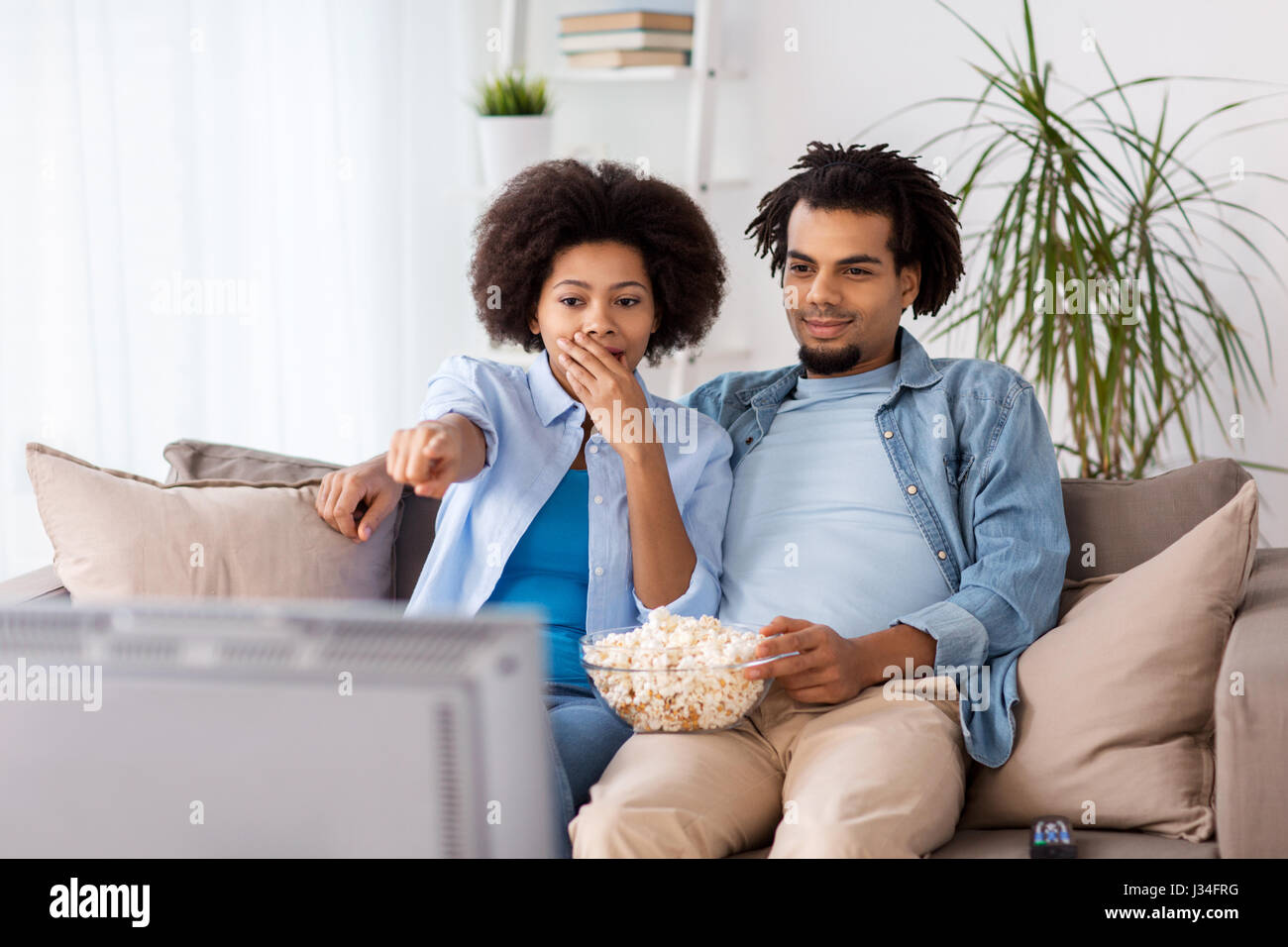 couple with popcorn watching tv at home Stock Photo - Alamy