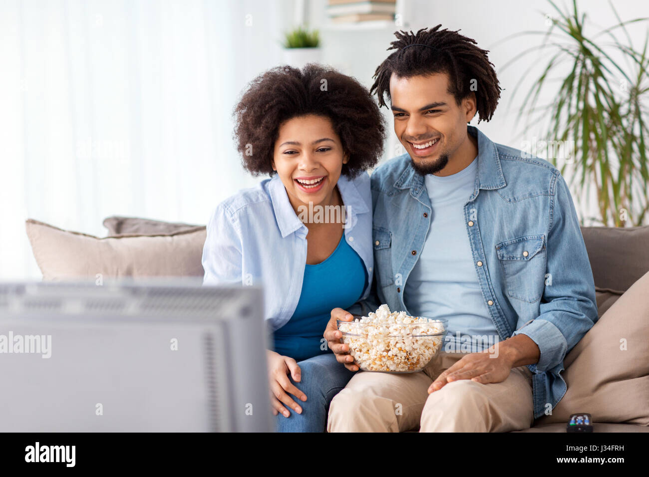smiling couple with popcorn watching tv at home Stock Photo - Alamy