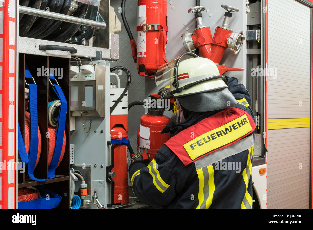 German firefighter with fire extinguisher on the fire truck Stock Photo