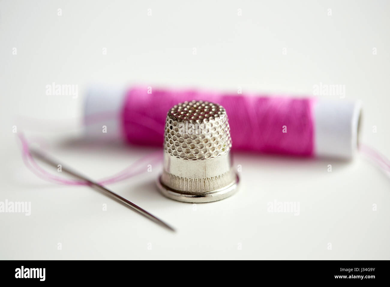thimble, sewing needle and thread spool Stock Photo Alamy