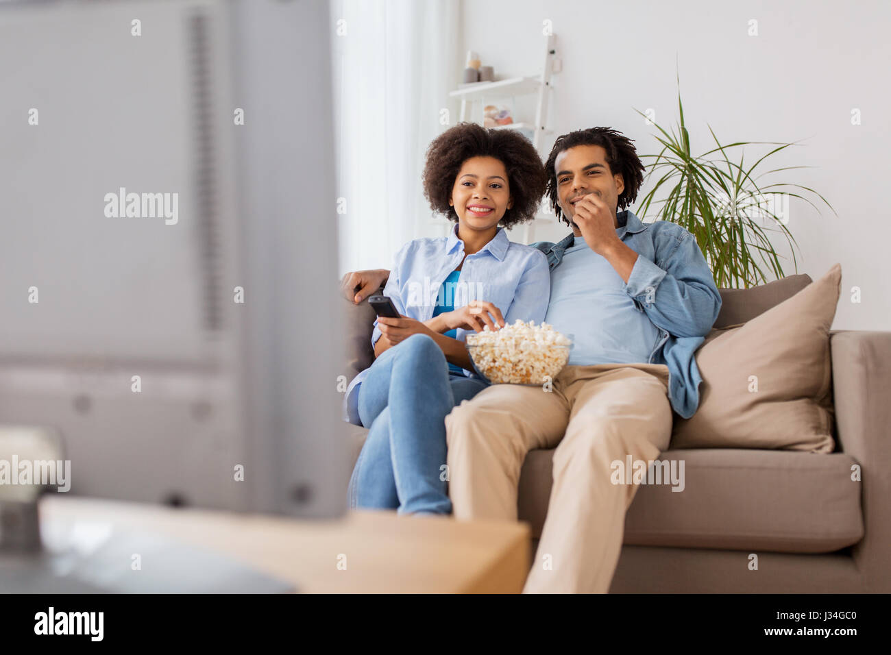 smiling couple with popcorn watching tv at home Stock Photo - Alamy
