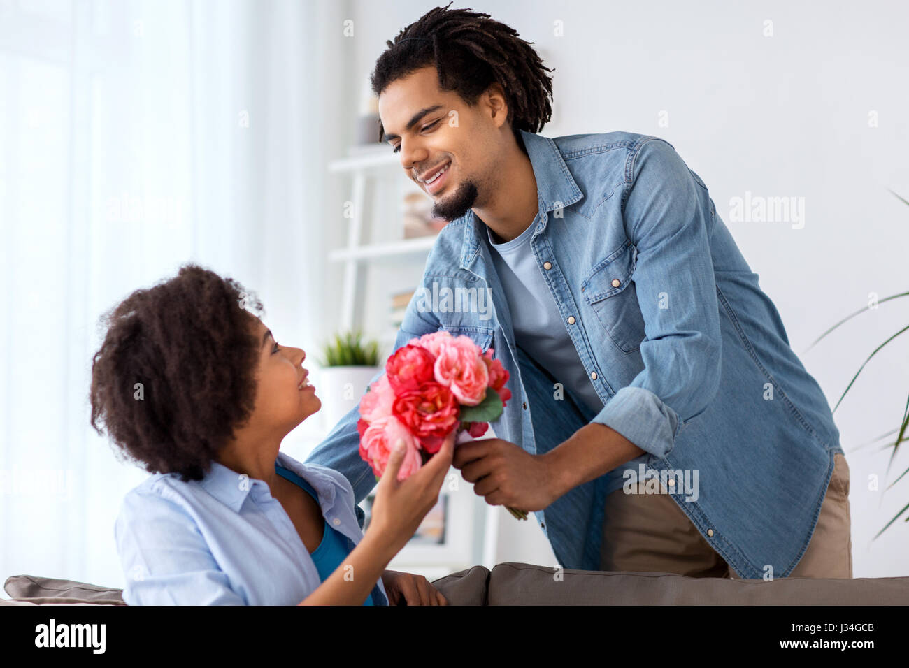 happy couple with bunch of flowers at home Stock Photo - Alamy