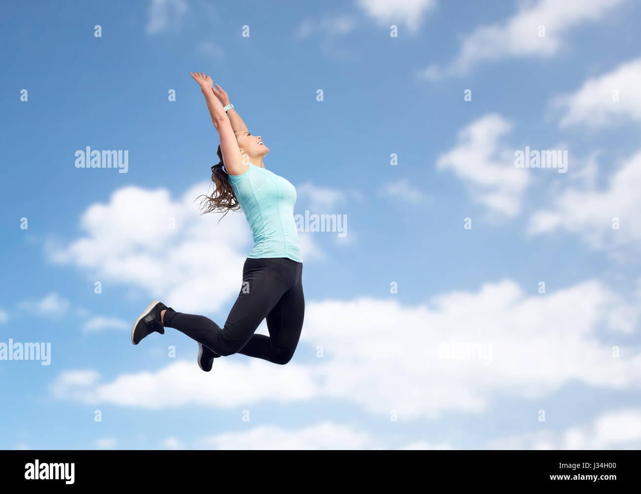 happy sporty young woman jumping in blue sky Stock Photo - Alamy