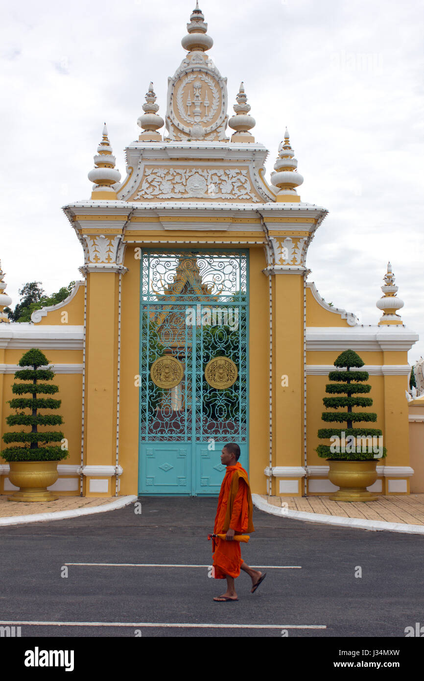 A Buddhist monk walks past an ornate gate of the Royal Palace, Phnom Penh, Cambodia. Stock Photo
