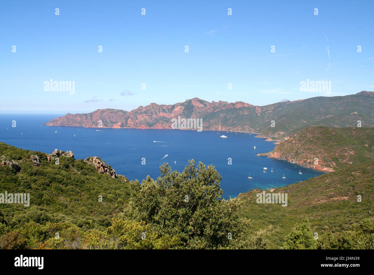 Red sandstone rocks and pristine waters of the Scandola Nature Reserve on the unspoilt coast of Corsica, France. Stock Photo