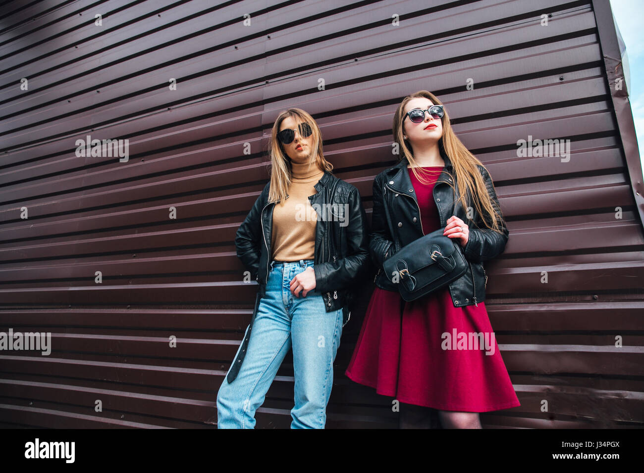 Two Women Talking in the City.Outdoor lifestyle portrait of two best friends hipster girls wearing stylish Leather Jacket and sunglasses, going crazy and having great time together Stock Photo