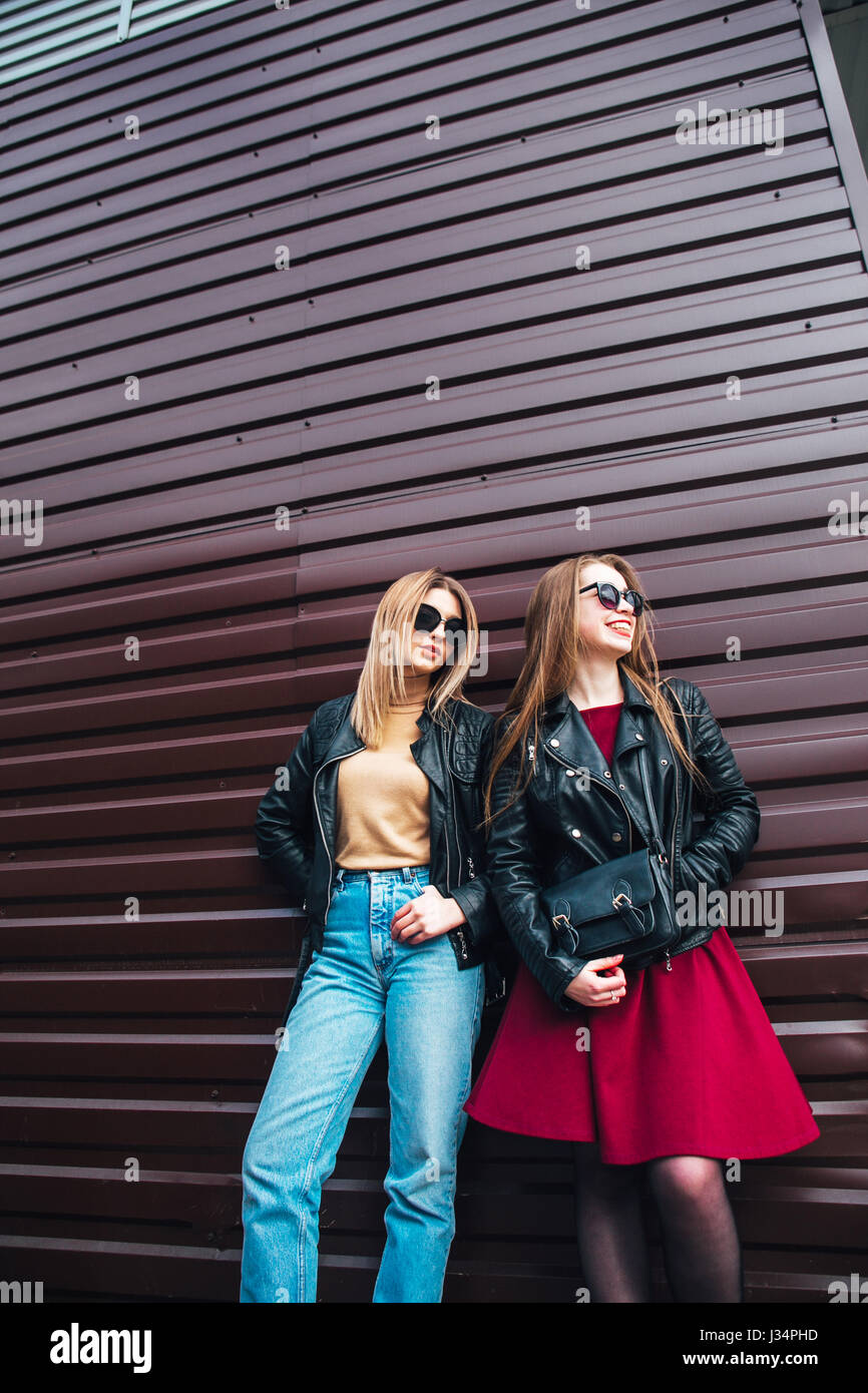 Two Women Talking in the City.Outdoor lifestyle portrait of two best friends hipster girls wearing stylish Leather Jacket and sunglasses, going crazy and having great time together Stock Photo