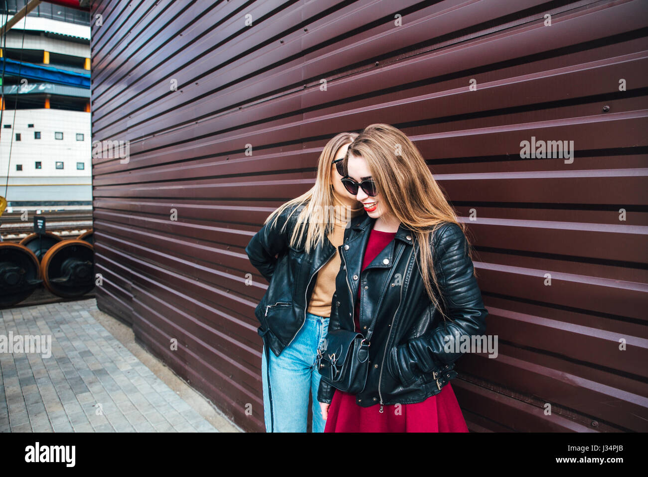 Two Women Talking in the City.Outdoor lifestyle portrait of two best friends hipster girls wearing stylish Leather Jacket and sunglasses, going crazy and having great time together Stock Photo
