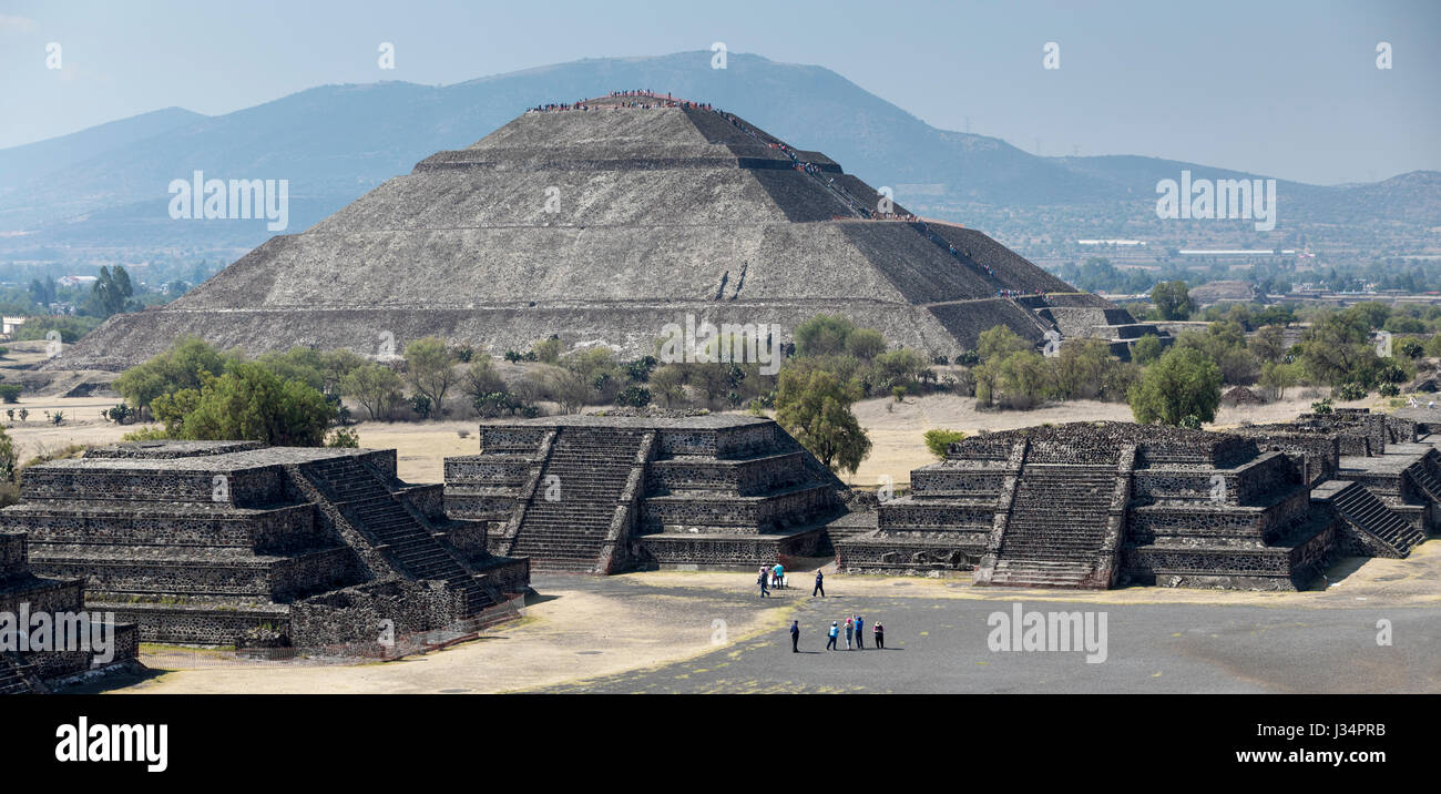 Teotihuacan, Mexico - 21 April 2017: Tourists atop and climbing the Pyramid of the Sun with other tourist in plaza in front of the Pyramid of the Moon Stock Photo