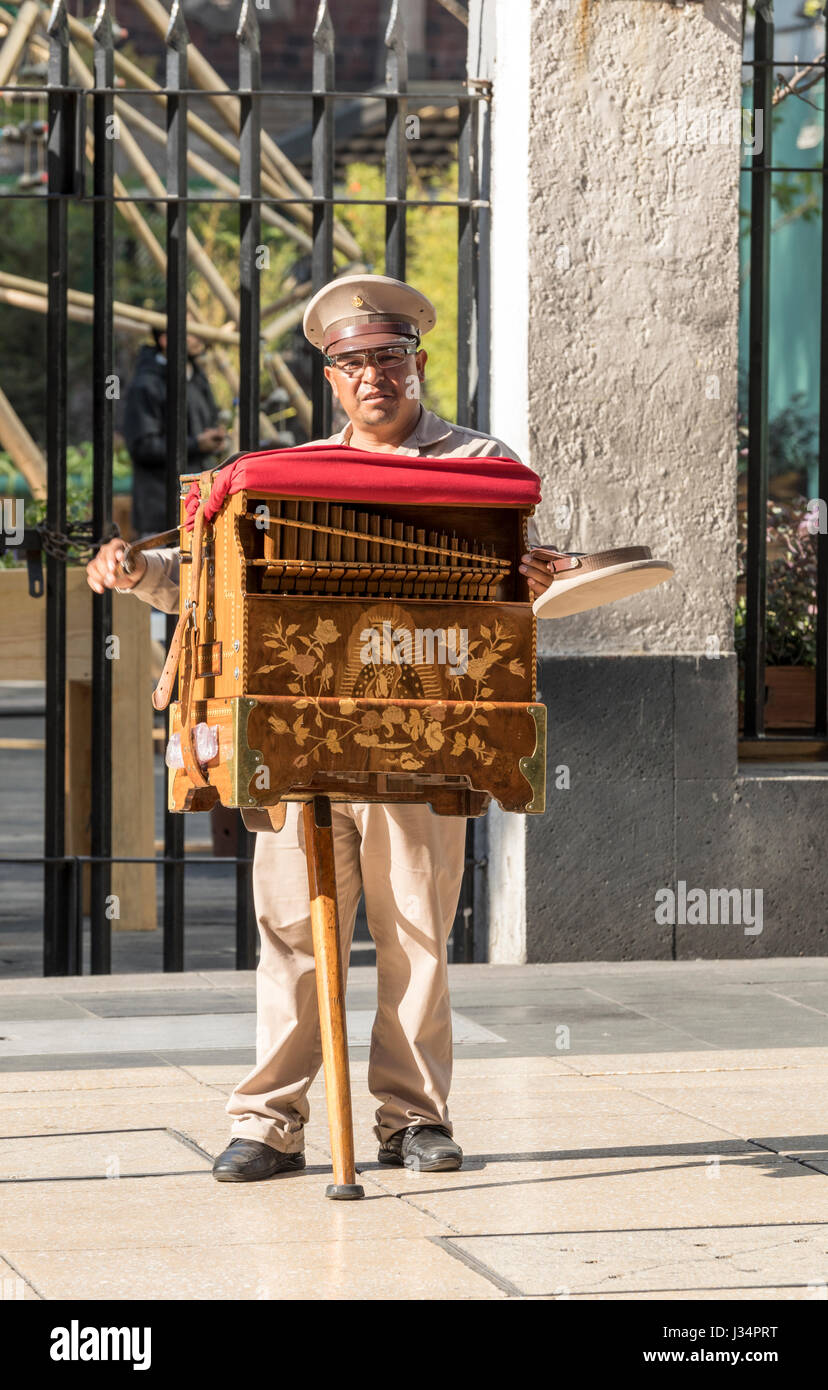 Mexico City, Mexico -22 April 2017: Traditional organ grinder cranks his organ while holding out a hat for donations on the Avenue Francisco Madero Stock Photo