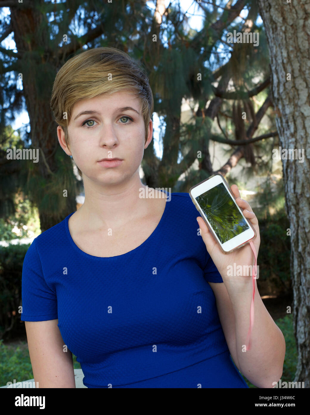 Model released image of young caucasian teenage blonde girl sad holding broken phone Stock Photo