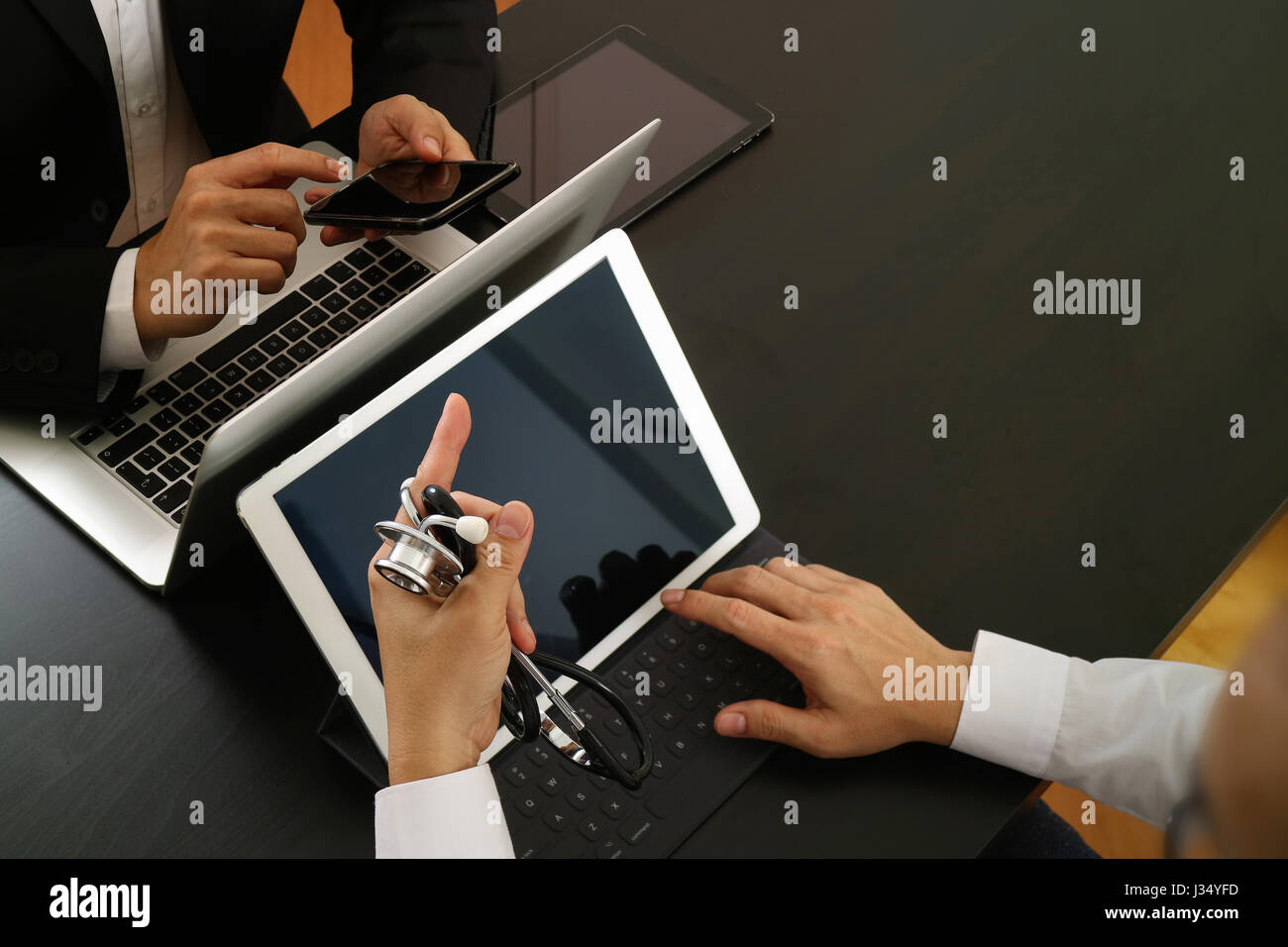 Medical co working concept,Doctor working with smart phone and digital tablet and laptop computer to meeting his team in modern office at hospital Stock Photo