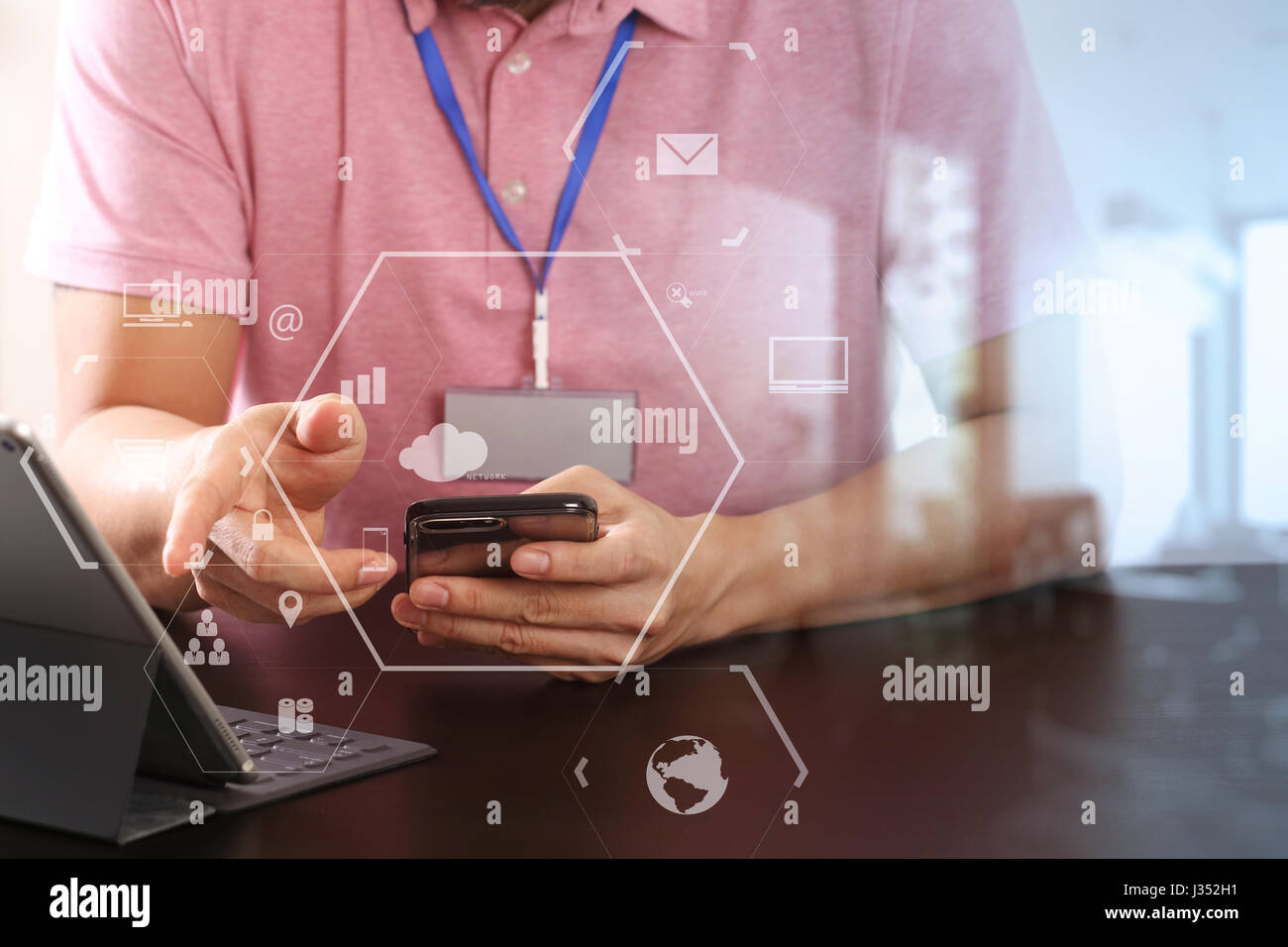 businessman in pink t-shirt working with smart phone and digitl tablet computer on wooden desk in modern office with virtual icon diagram Stock Photo