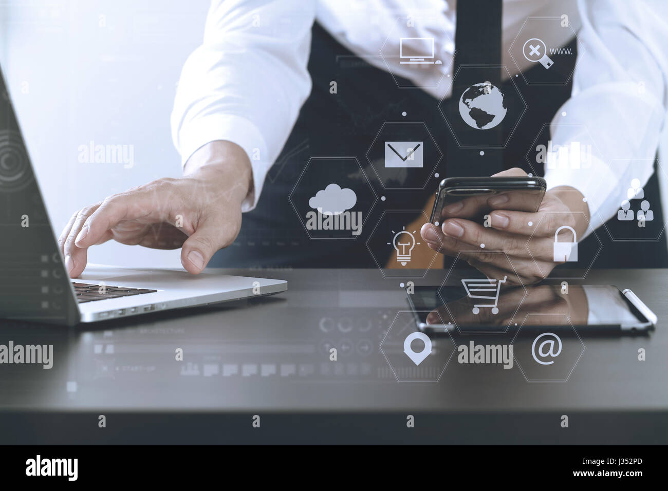 close up of businessman working with smart phone and laptop and digital tablet computer in modern office with virtual icon diagram Stock Photo