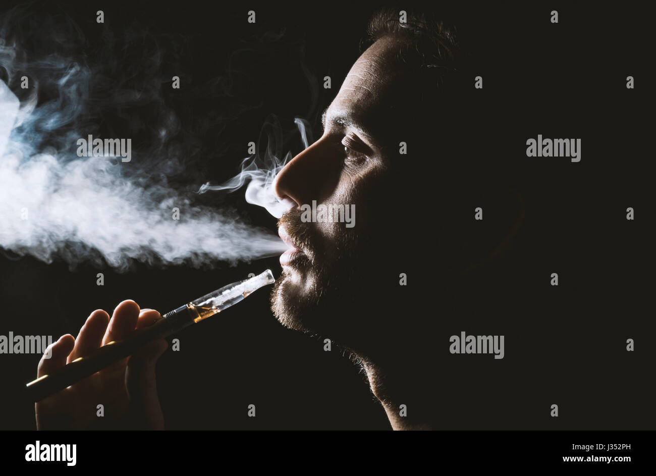 Young man holding and vaping an electronic cigarette, e-cig, ecigarette. Stock Photo