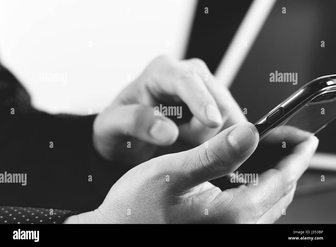 close up of businessman hand working with smart phone and laptop and digital tablet computer in modern office,black and white Stock Photo
