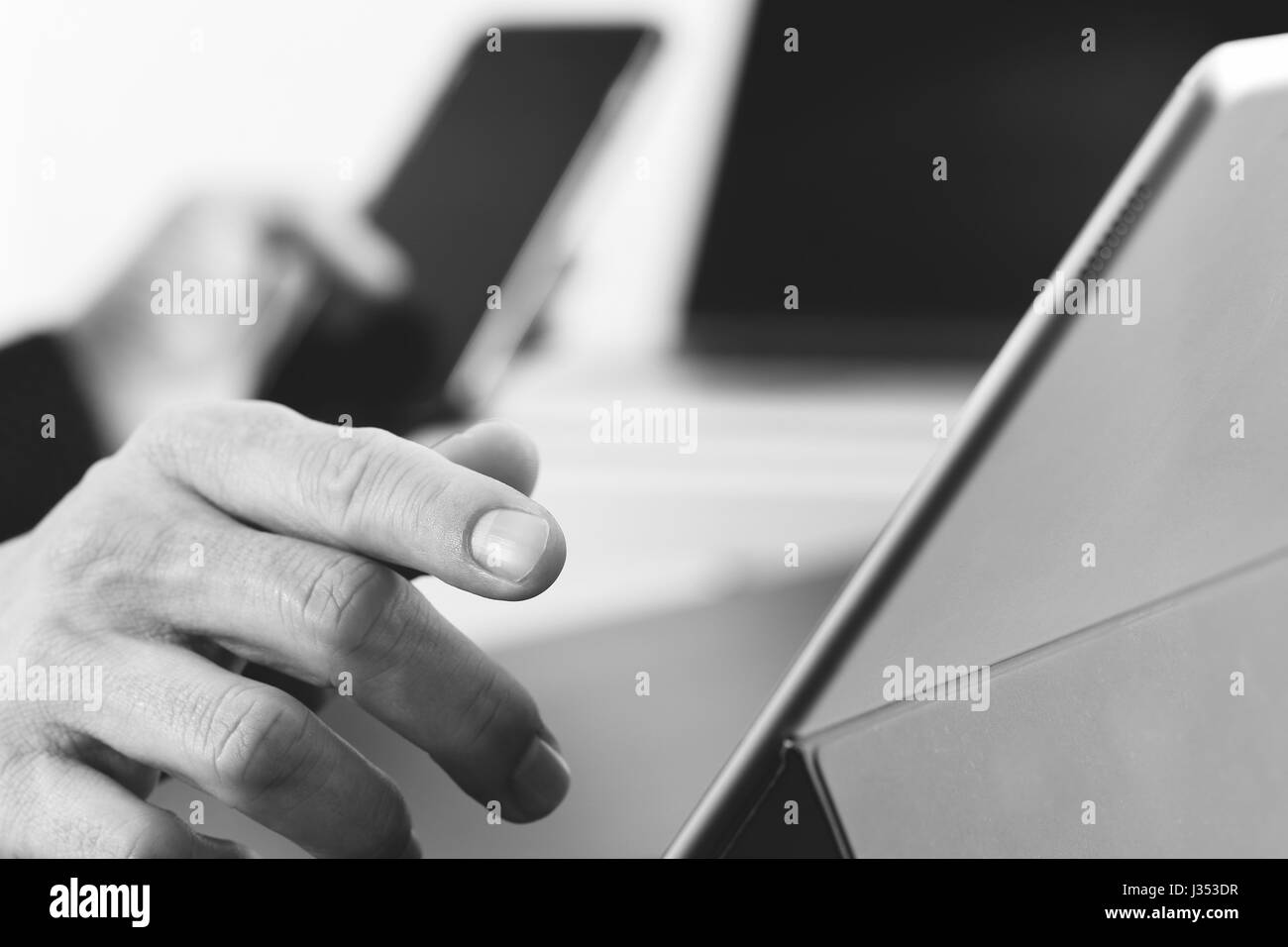 close up of businessman hand working with smart phone and laptop and digital tablet computer in modern office,black and white Stock Photo