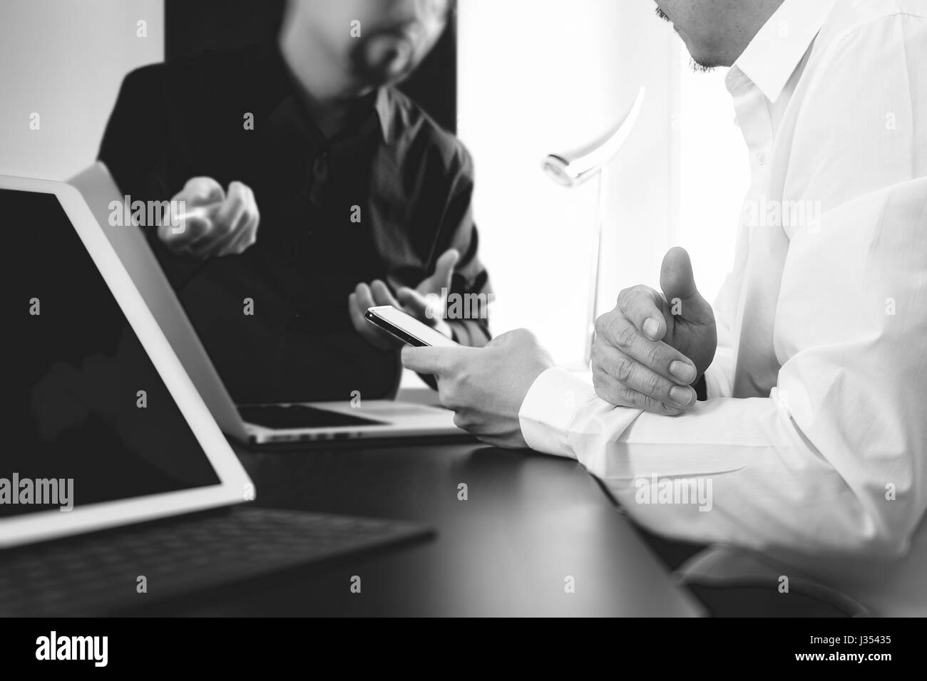 co working team meeting concept,businessman using smart phone and digital tablet and laptop computer in modern office,black and white Stock Photo