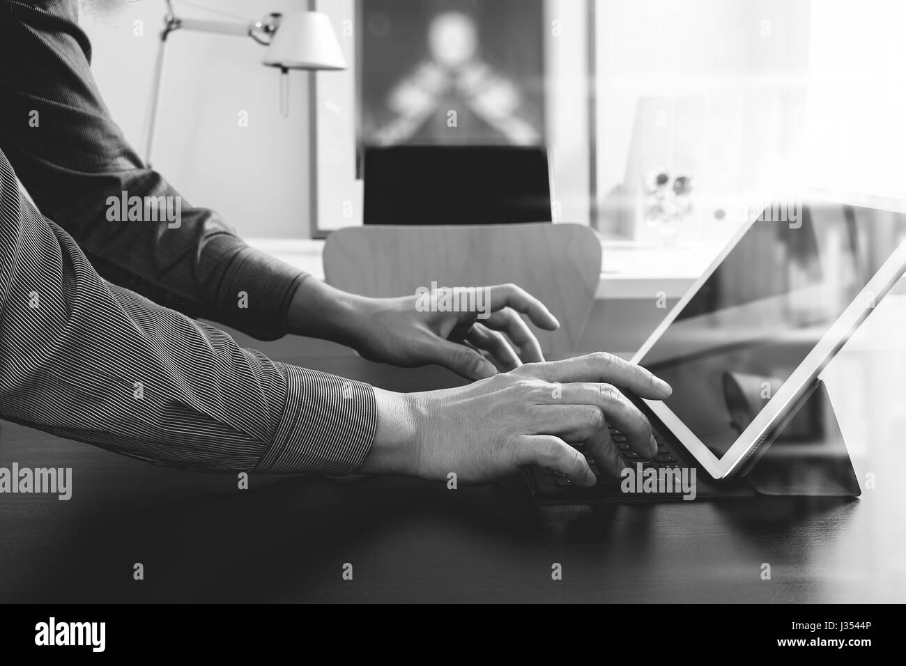 businessman or Designer using digital tablet computer on black desk in modern office,black and white Stock Photo