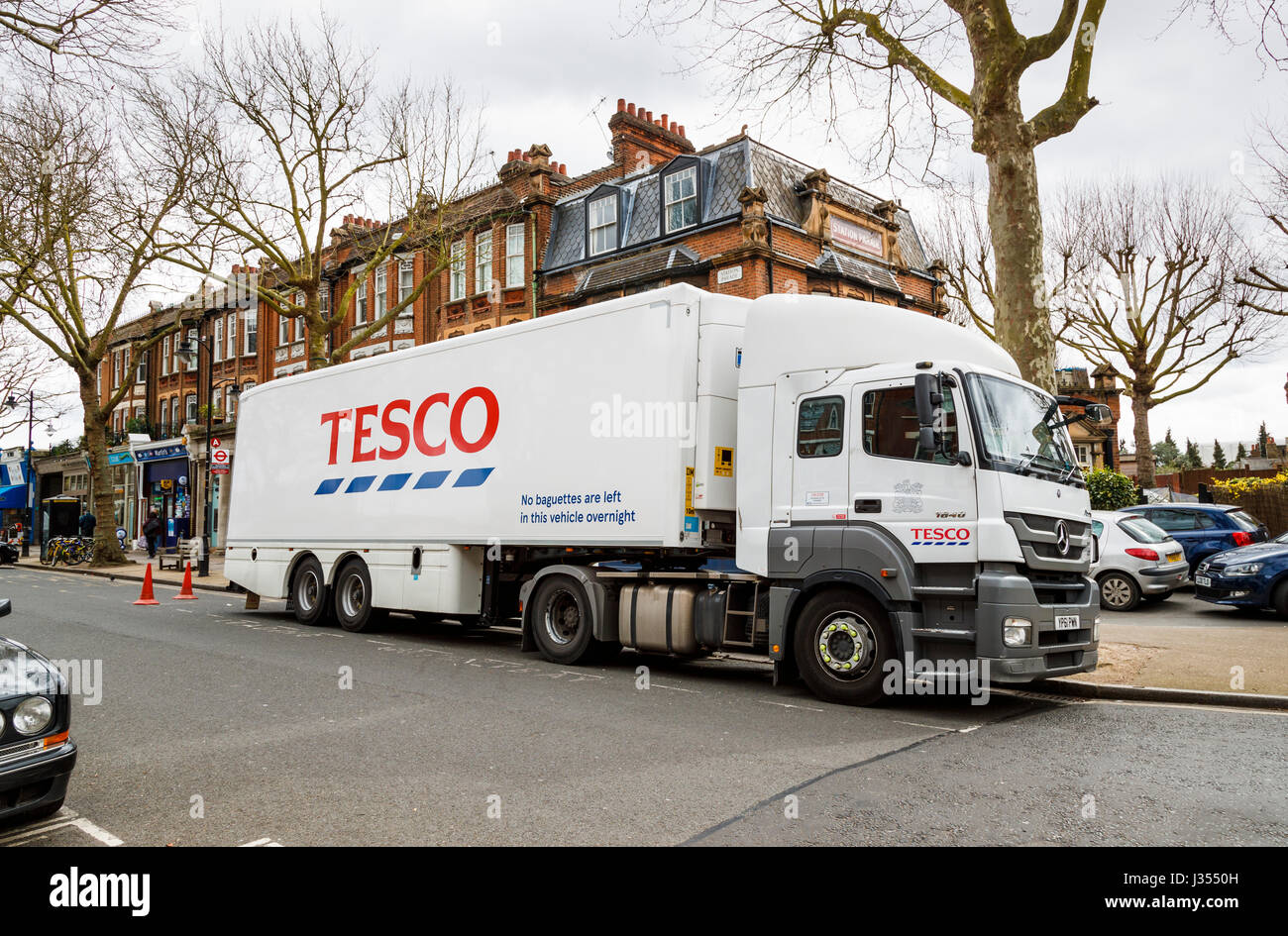 Large white Tesco delivery lorry with Tesco logo on its side making a delivery parked outside Tesco Express store, Station Parade, Kew, Richmond, TW9 Stock Photo