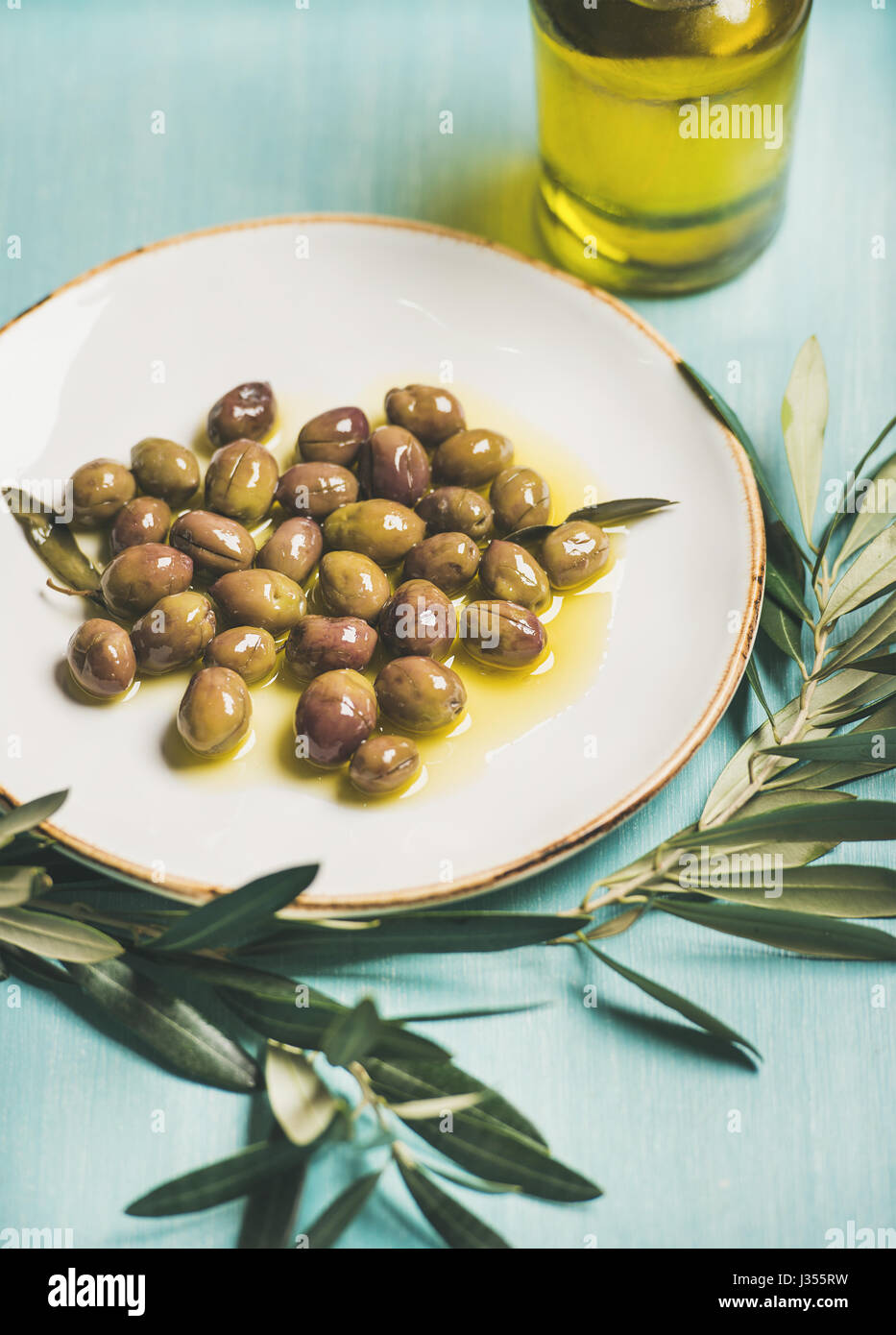 Pickled green olives, olive tree branch, virgin oil, selective focus