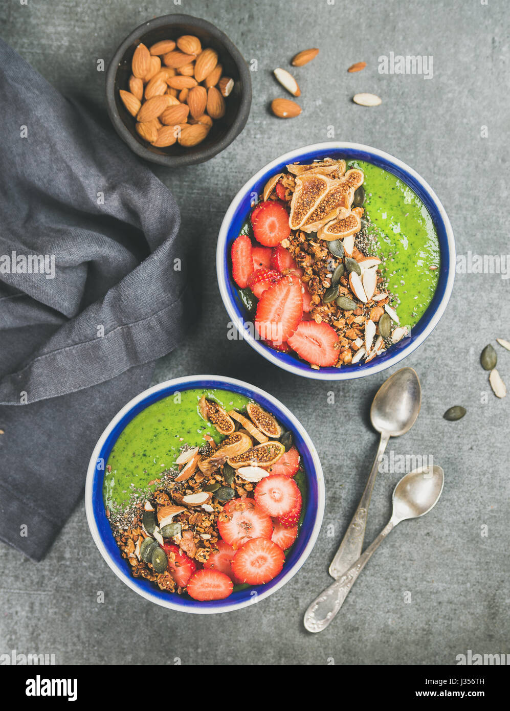 Healthy green smoothie breakfast bowls with granola, fruit, seeds