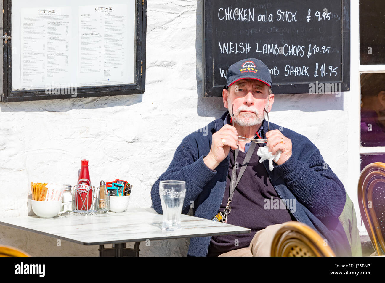 A person sitting outdoors in the sunshine at the Cottage Tea Rooms on the highstreet of Llangollen in North Wales Stock Photo
