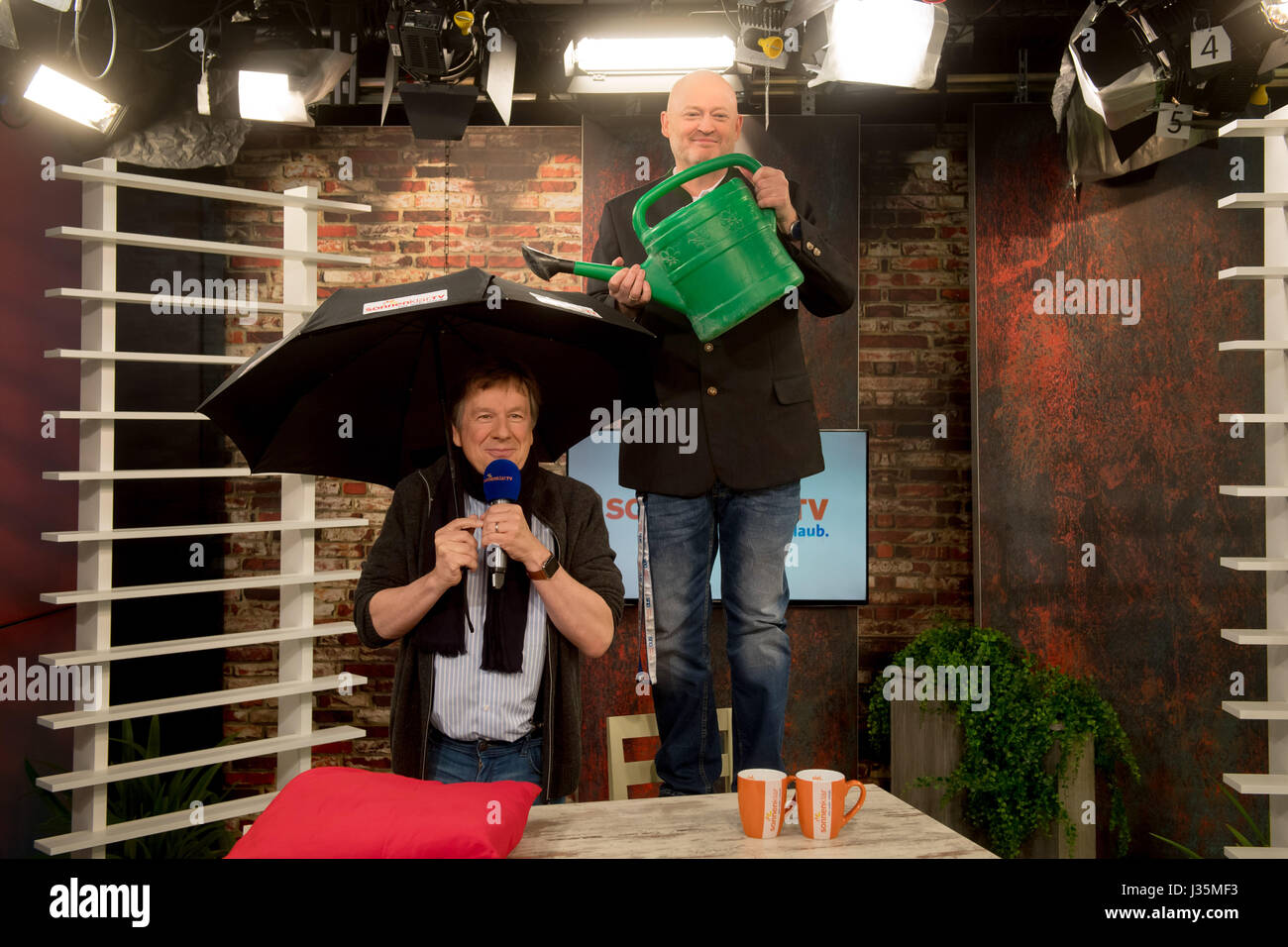 Munich, Germany. 03rd May, 2017. Andreas Lambeck (R), CEO of the sonnenklar.TV TV station, uses a watering can to pour water on the head of meteorologist Jorg Kachelmann at the TV studio of the sonnenklar.TV station in Munich, Germany, 03 May 2017. On 04 May Kachelmann will present the 'Kachelmannwetter' show, which will air once monthly. Photo: Tobias Hase/dpa/Alamy Live News Stock Photo