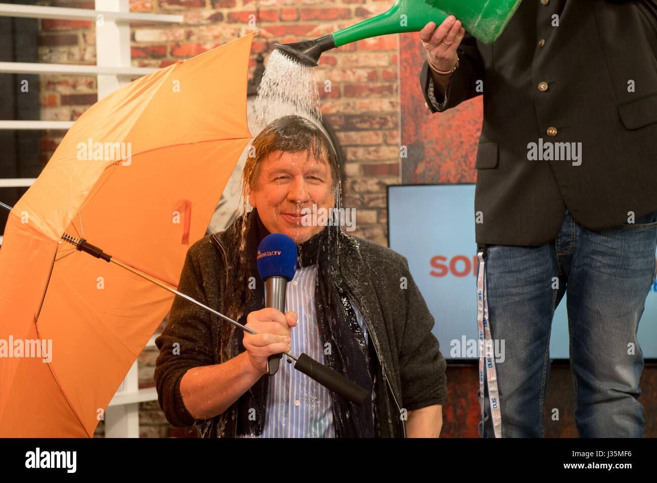 Munich, Germany. 03rd May, 2017. Andreas Lambeck (R), CEO of the sonnenklar.TV TV station, uses a watering can to pour water on the head of meteorologist Jorg Kachelmann at the TV studio of the sonnenklar.TV station in Munich, Germany, 03 May 2017. On 04 May Kachelmann will present the 'Kachelmannwetter' show, which will air once monthly. Photo: Tobias Hase/dpa/Alamy Live News Stock Photo