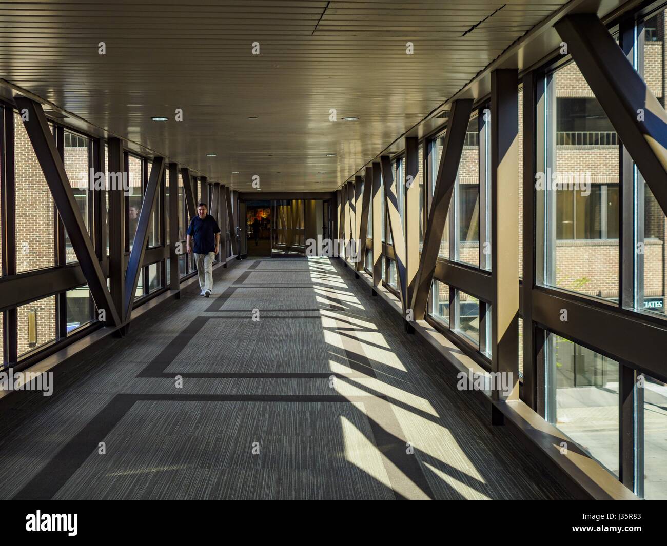 May 3, 2017 - Minneapolis, Minnesota, U.S - A person in a Minneapolis skyway. The skyways are enclosed pedestrian overpasses that connect downtown buildings. The Minneapolis Skyway was started in the early 1960s as a response to covered shopping malls in the suburbs that were drawing shoppers out of the downtown area. The system grew sporadically until 1974, when the construction of the IDS Center and its center atrium, called the Crystal Court, served as a hub for the downtown skyway system. There are 8 miles of skyways, connecting most of the downtown buildings from Target Field (home of the Stock Photo