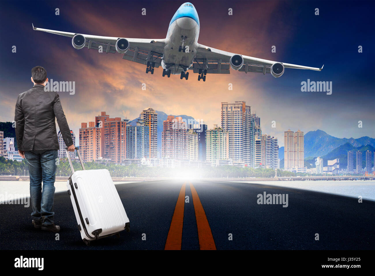 young man with belonging luggage standing  against urban scen and passenger jet plane flying over sky use for people traveling and aircraft transport  Stock Photo