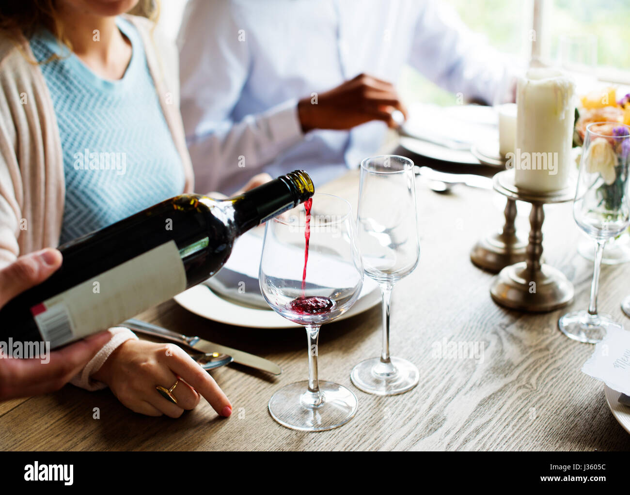 Waiter Poring Serving Red Wine to Customers in a Restaurant Stock Photo