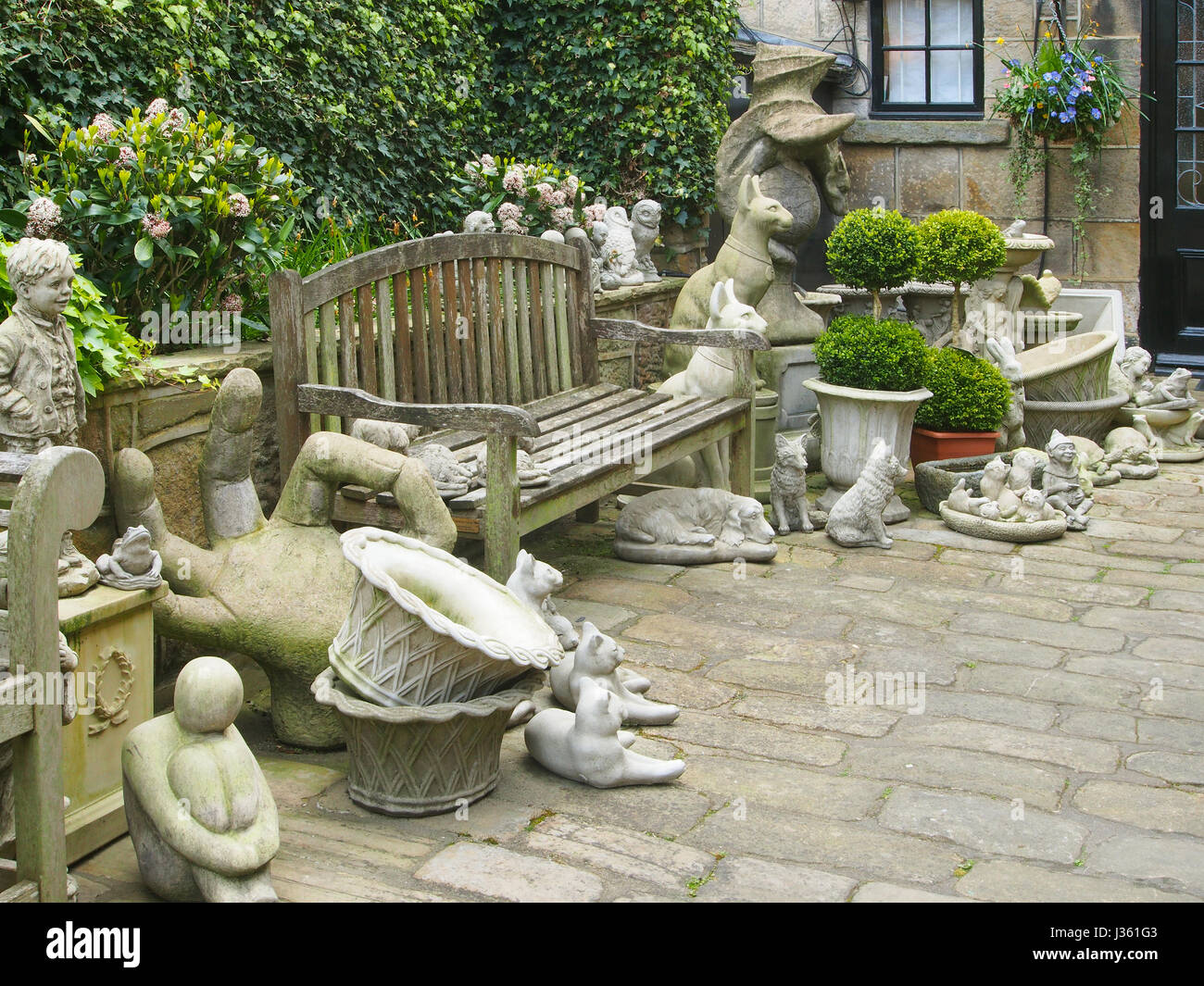 Cobbled courtyard of a shop in Montpellier Mews in Montpellier, Harrogate, Yorkshire, selling garden ornaments, including a grotesque Punch and Judy. Stock Photo