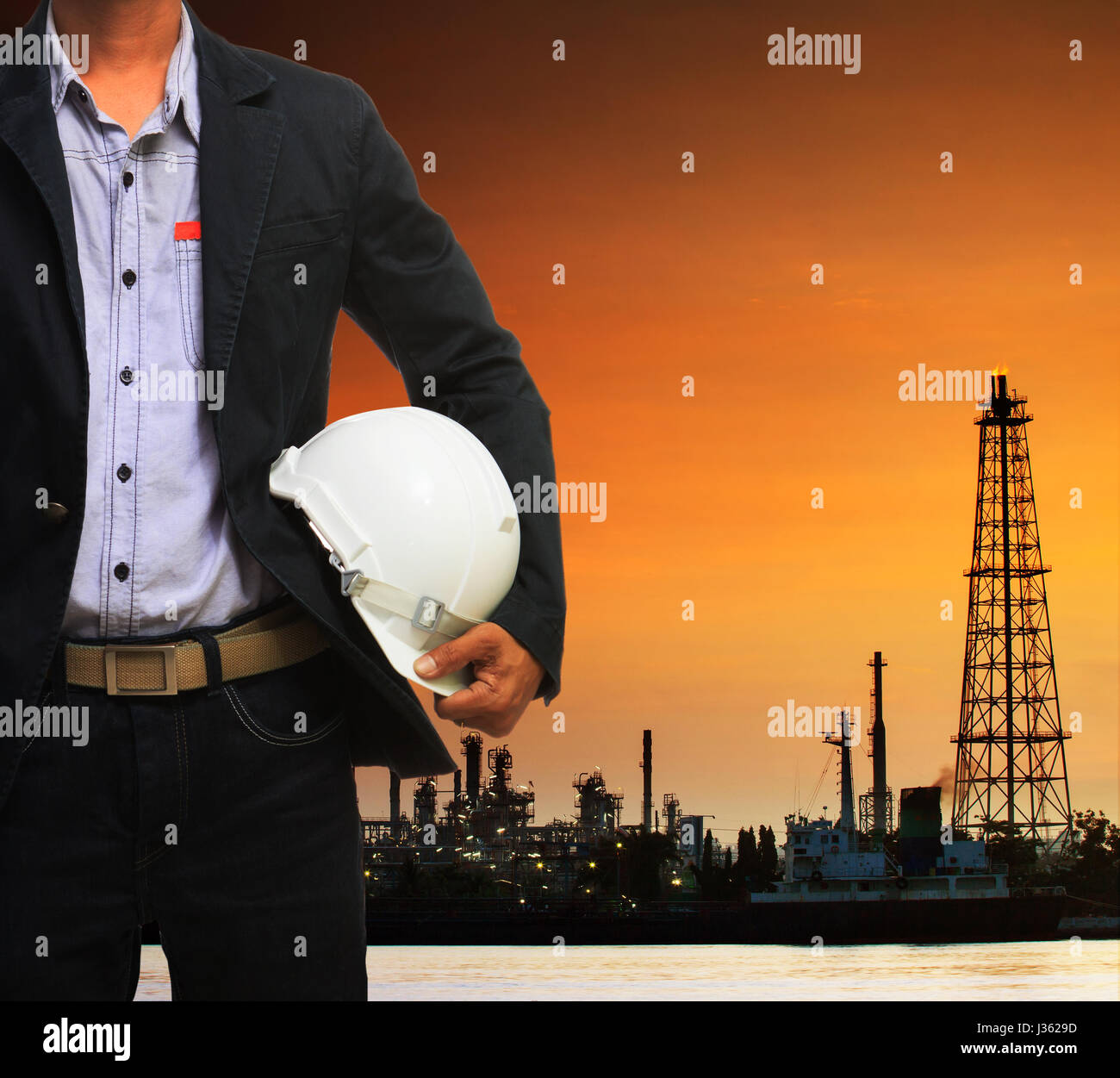 engineering man and safety helmet standing against beautiful dusky sky of oil refinery plant