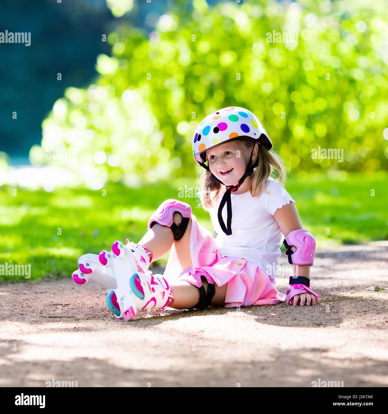 Little Girl Learning To Roller Skate In Sunny Summer Park. Child Wearing  Protection Elbow And Knee Pads, Wrist Guards And Safety Helmet For Safe  Roller Skating Ride. Active Outdoor Sport For Kids.